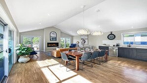 A spacious kitchen with a dining area, a fireplace, and a large window. - FIGTREE RETREAT - THE VINTAGE HOLIDAY HOUSES (POKOLBIN)