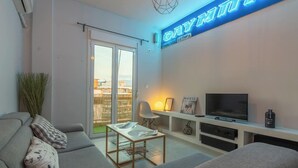Een moderne woonkamer met een bank, salontafel, televisie en een neonbord.