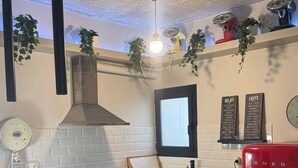 Een keuken met een centraal kookeiland, een rode koelkast, een hanglamp en een raam met uitzicht.