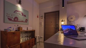 Een moderne keuken met een houten kast, een laptop op het aanrecht en een groot schilderij met een auto-thema aan de muur.