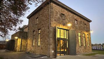 A stone building with large windows and a door, illuminated by exterior lights.