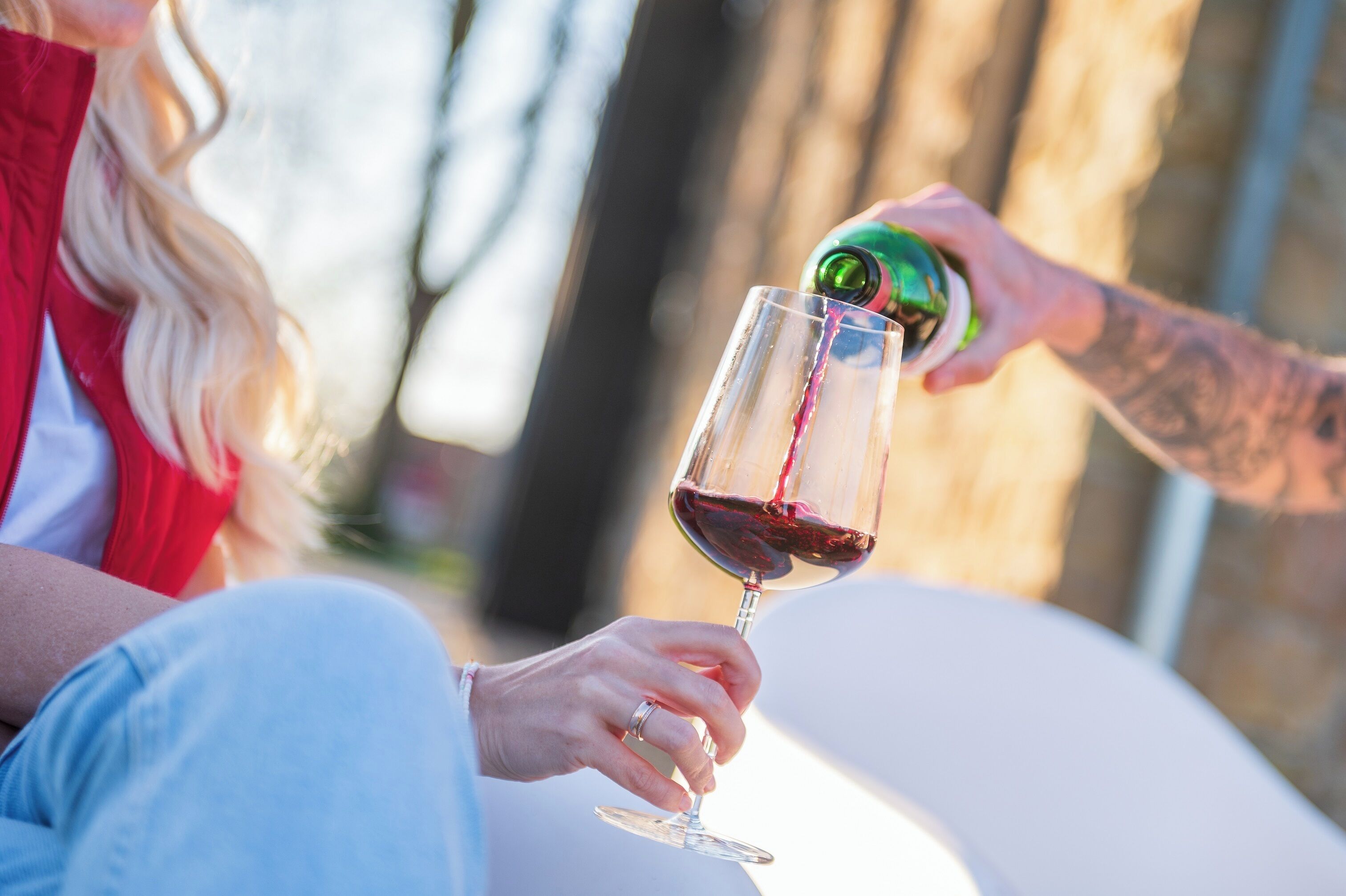 A person pouring red wine into a glass.
