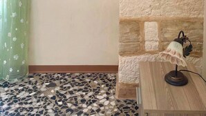 Una habitación de esquina con una repisa blanca, suelo estampado y pared de piedra.