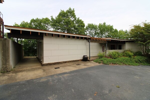 A single-story building with a garage, a covered porch, and a small garden area. - Greers Ferry Lake Modern (Edgemont)
