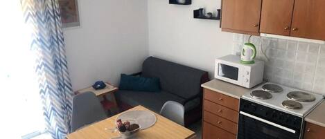 Una cocina compacta con microondas, estufa y armarios de madera.