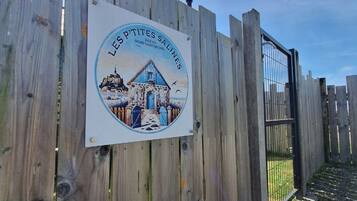 A wooden fence with a sign that reads "LES P'tites Salines" and depicts a building with a blue roof.