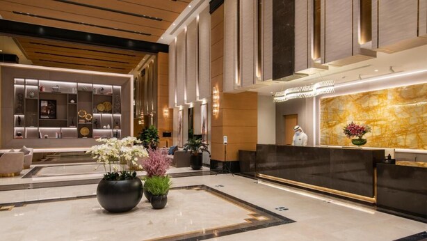 Un'ampia hall con reception, area salotto e piante ornamentali.