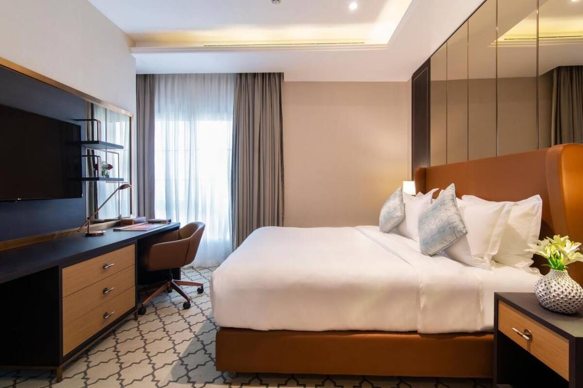 Una habitación de hotel con una cama, un escritorio, una silla, un televisor y un armario.