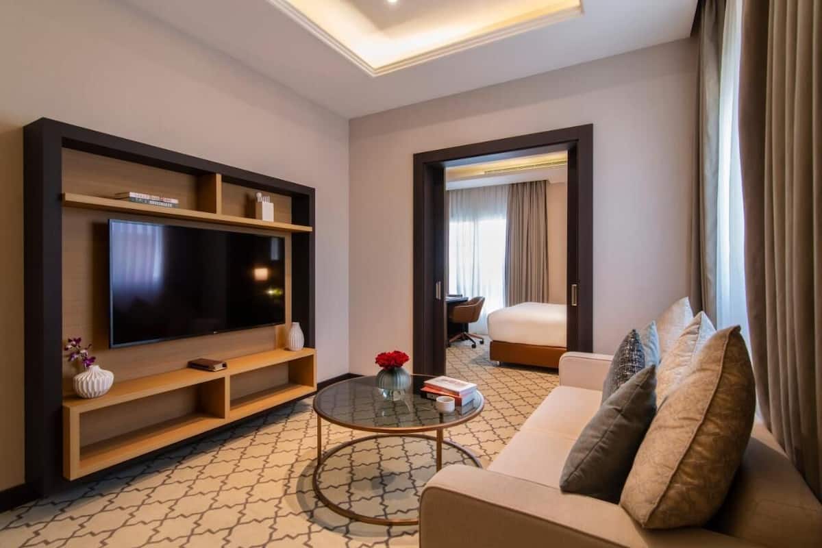 Una habitación de hotel moderna con una televisión de pantalla grande, un sofá, una mesa de centro y una cama.