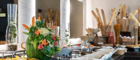Montaje de bufé con un gran centro de flores, cuencos blancos y diferentes tipos de comida.