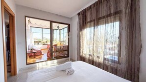 Hotellihuone, jossa on suuri sänky, liukuovet, jotka johtavat ulkotilalle, ja näkymä ulos.