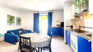A compact living space with a dining area, kitchenette, and a sofa.