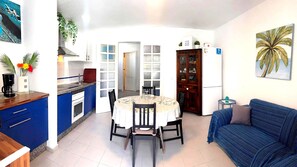 A compact living space with a dining area, kitchenette, and a sofa.