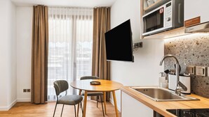A modern kitchen with a flat-screen TV, a sink, and a microwave. - Limehome Piraeus Port (Piraeus)