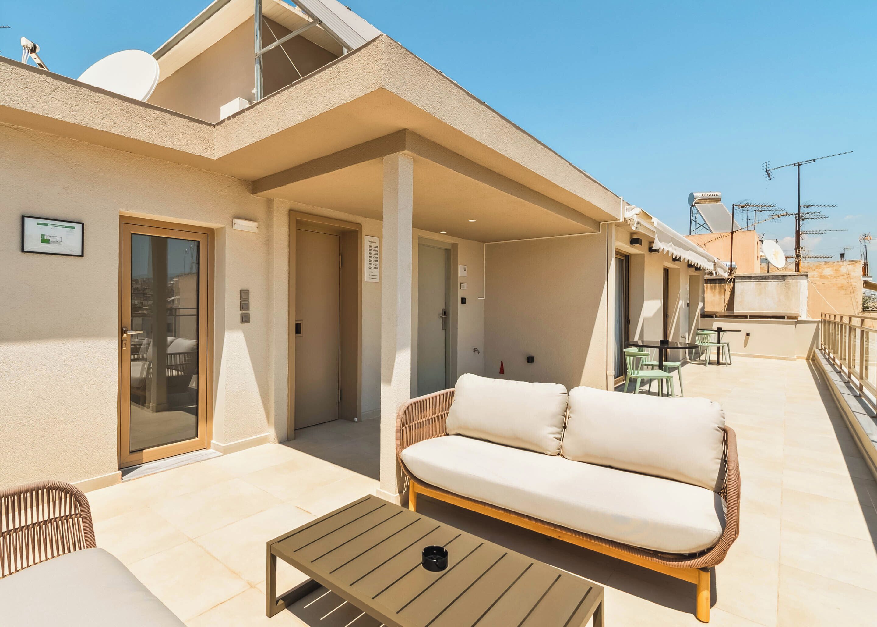 A balcony with a sofa and a table, a door, and a small sign on the wall.