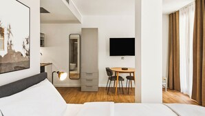 A hotel room with a bed, a desk with a chair, a television, and a bathroom visible through an open door. - Limehome Piraeus Port (Piraeus)