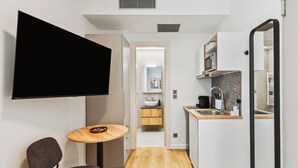 A compact kitchen with a sink, countertop, and a television mounted on the wall. - Limehome Piraeus Port (Piraeus)