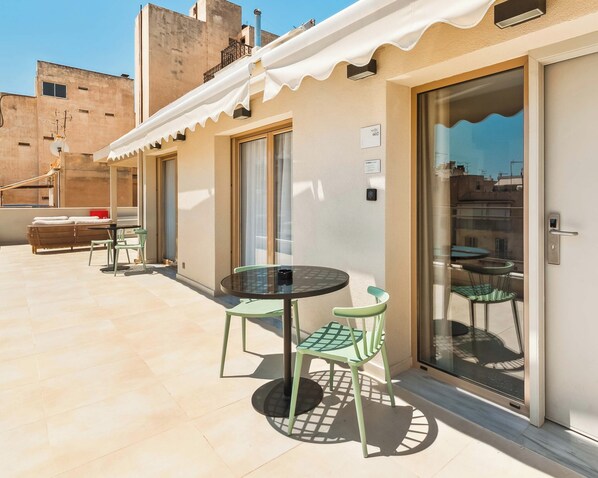 A rooftop terrace with a table and chairs, a sofa, and a sliding glass door. - Limehome Piraeus Port (Piraeus)