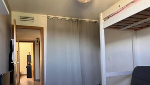 A room with a bunk bed, a desk, a chair, a curtain, and a door leading to another room. - Quiet house on the Côte d'Azur (Cagnes-sur-Mer)