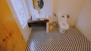 Kylpyhuone, jossa on ruutukuviollinen lattia, valkoinen pesuallas peilillä ja wc-istuin.