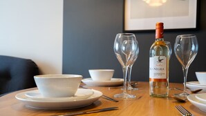 A dining table with a bottle of Isla Negra Sauvignon Blanc, two wine glasses, and white bowls on plates. - Crookesmoor View, Sheffield (South Yorkshire)