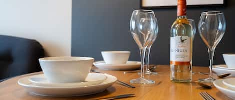 Une table à manger avec une bouteille de vin blanc Isla Negra Sauvignon Blanc, deux verres à vin et des bols blancs posés sur des assiettes.
