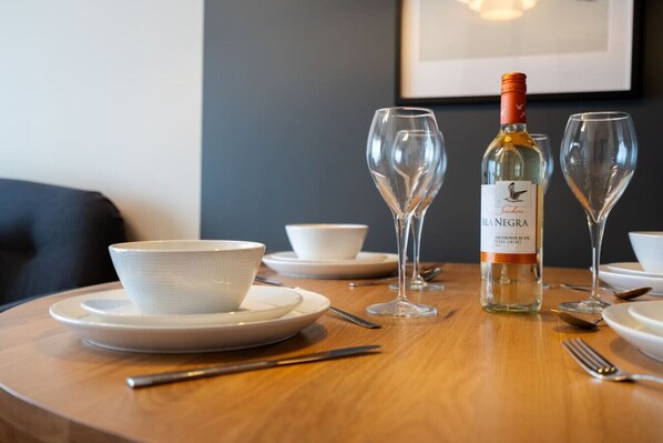 A dining table with a bottle of Isla Negra Sauvignon Blanc, two wine glasses, and white bowls on plates. - Crookesmoor View, Sheffield (South Yorkshire)