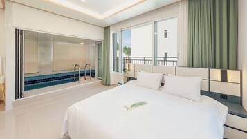 Une chambre d’hôtel avec un grand lit, une salle de bain avec baignoire et un balcon avec des rideaux.