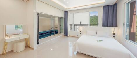 Una habitación de hotel moderna con una cama grande, un baño con ducha de vidrio, un balcón con vistas y un escritorio con espejo.