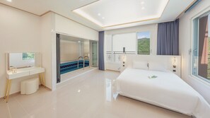 A modern hotel room with a large bed, a bathroom with a glass shower, a balcony with a view, and a desk with a mirror. - Gapyeong Laonjena Pool Villa (Gapyeong)