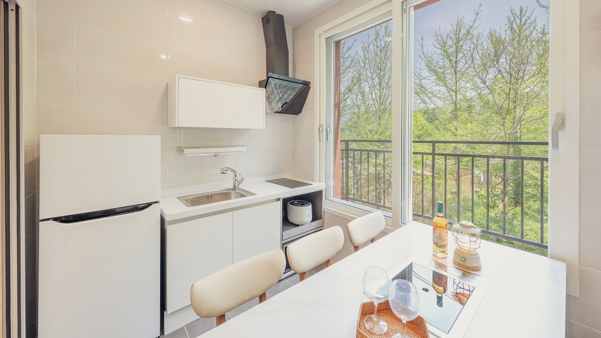 Cocina compacta con refrigerador, pileta y televisor de pantalla plana colocado sobre la encimera.