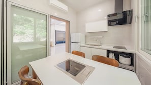 A modern kitchen with a built-in oven, a coffee machine, and a window overlooking a garden. - Gapyeong Laonjena Pool Villa (Gapyeong)