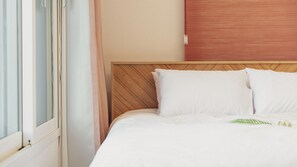 Ein Hotelzimmer mit Bett, Holz-Kopfteil und einem fensterbepflanzten Fenster.