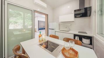 Una cocina moderna con comedor, refrigerador, pileta y ventana con vista a follaje.