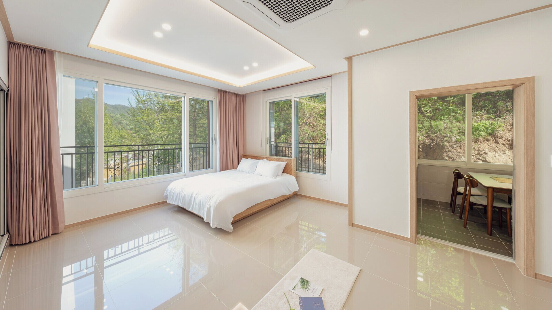 Une chambre moderne dotée d’un grand lit, d’un balcon et d’un coin repas offrant une vue sur l’extérieur.