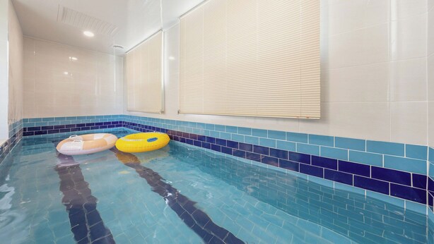 An indoor swimming pool with blue-tiled walls, two inflatable rings, and a ceiling with recessed lighting. - Gapyeong Laonjena Pool Villa (Gapyeong)