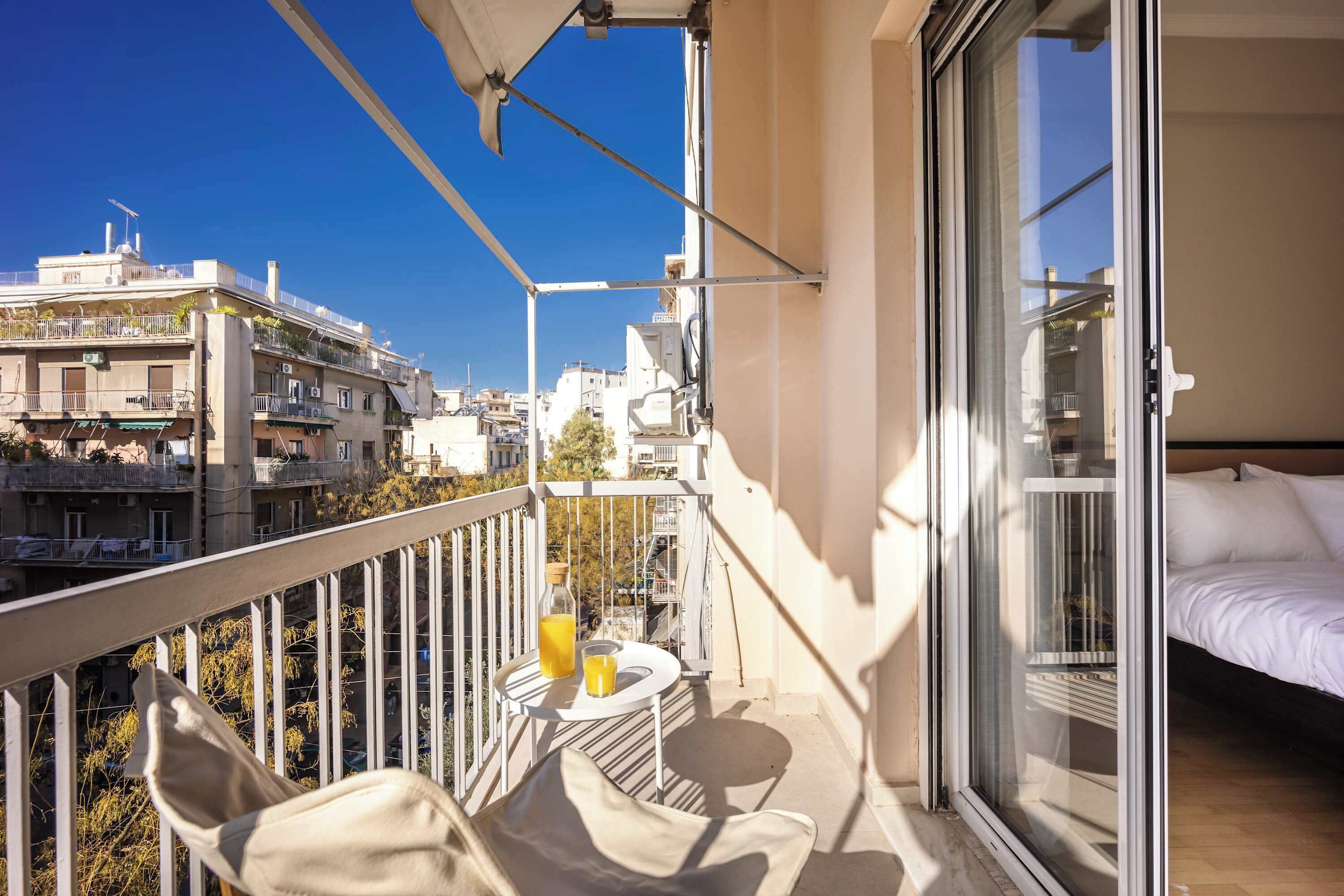 A balcony with a table, chairs, and a bottle of orange juice.