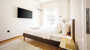 A modern bedroom with a bed, bedside table, and a mounted TV.