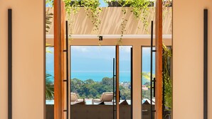 Une chambre moderne dotée d’une grande porte-fenêtre coulissante donnant sur un balcon avec vue sur l’océan.