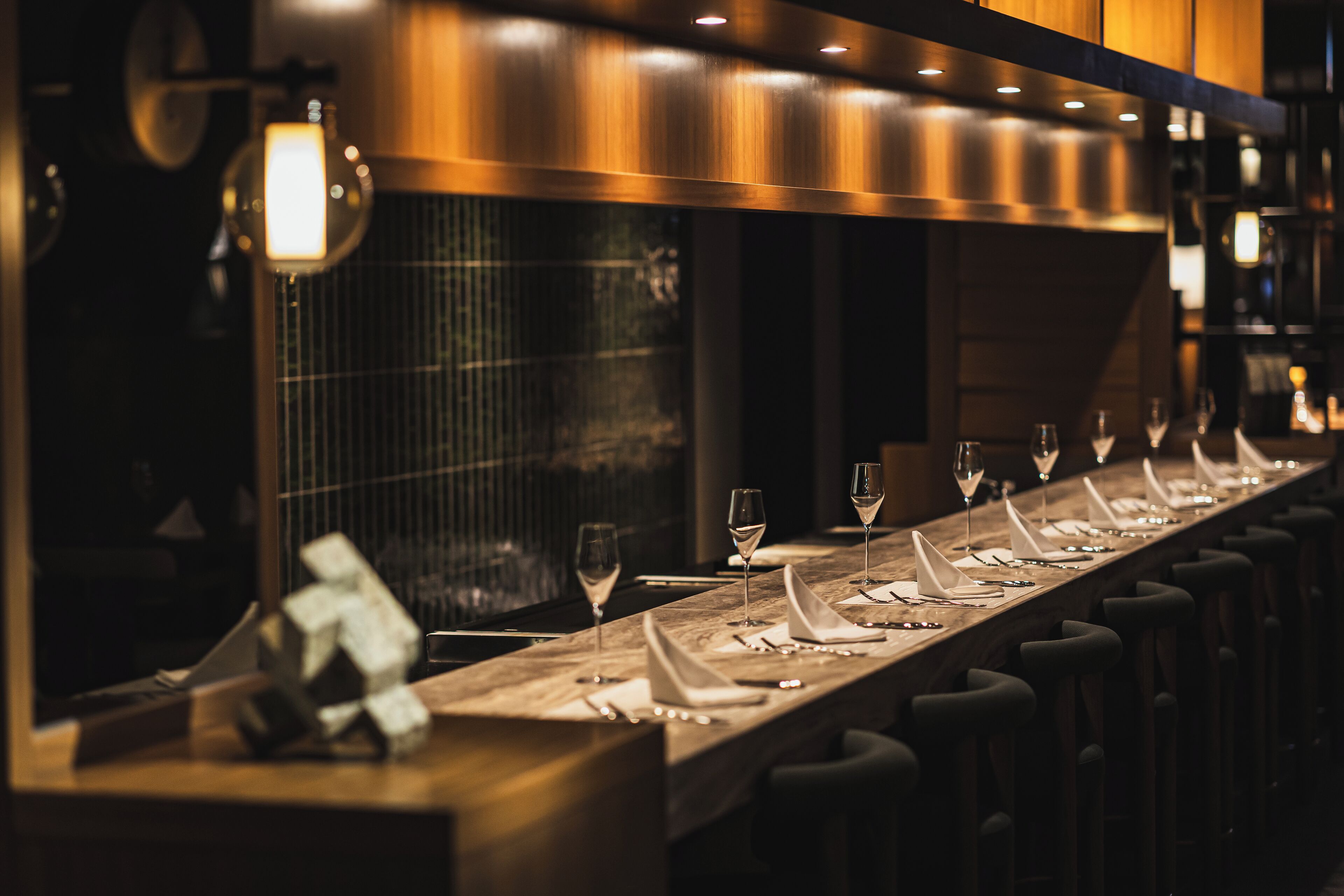 A long dining table with multiple chairs, each with a napkin and a glass of water.