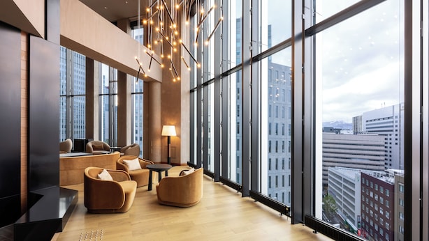 A modern interior with large windows, a sofa, a table, and a lamp. - THE GATE HOTEL SAPPORO by HULIC (Sapporo)