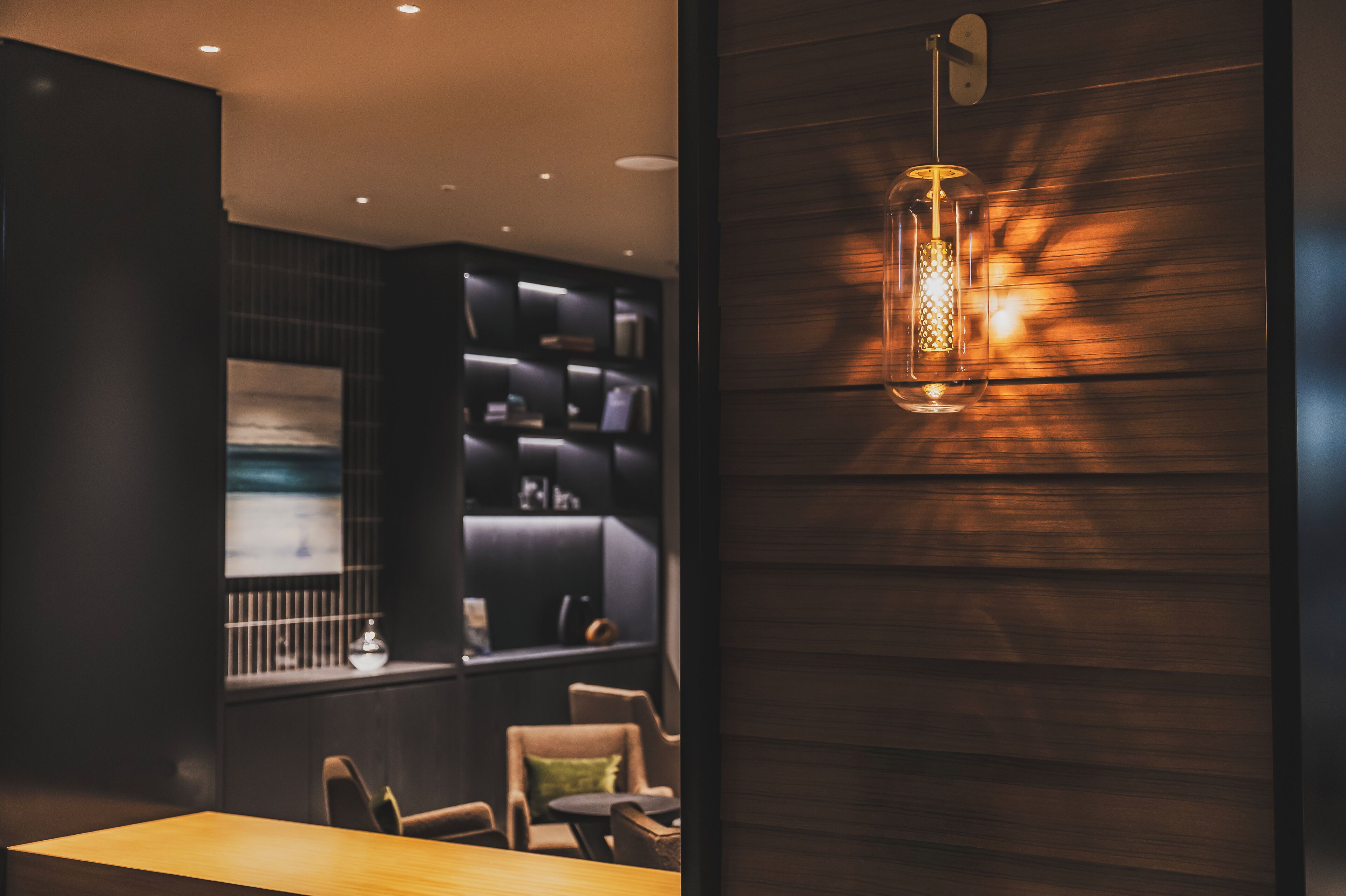 A modern interior with a wooden wall, a hanging light fixture, and a seating area with a table and chairs.