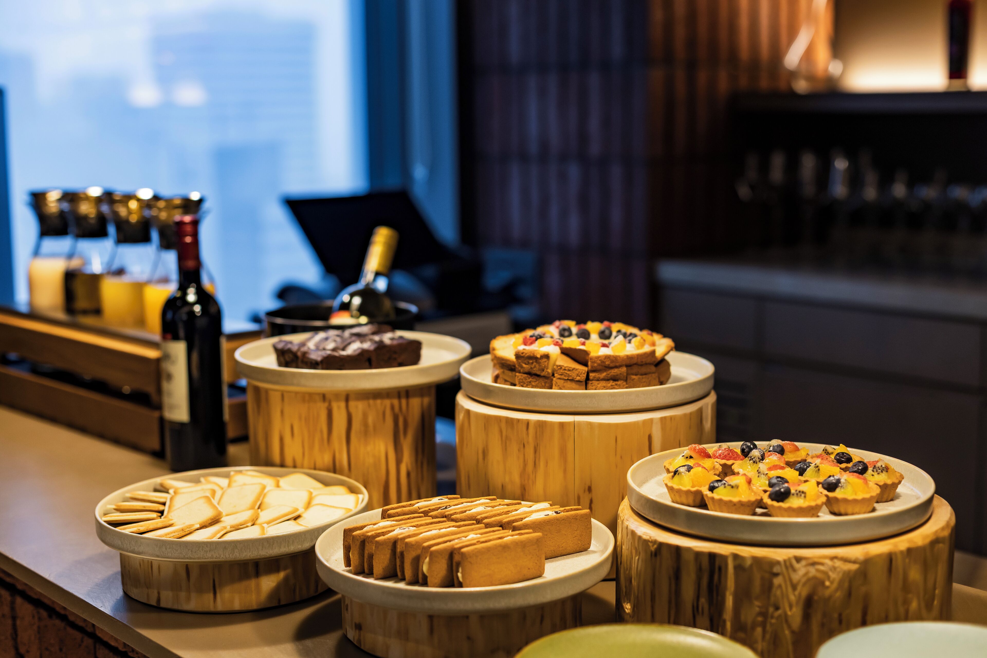 A bar area with wooden tables displaying various desserts and bottles.