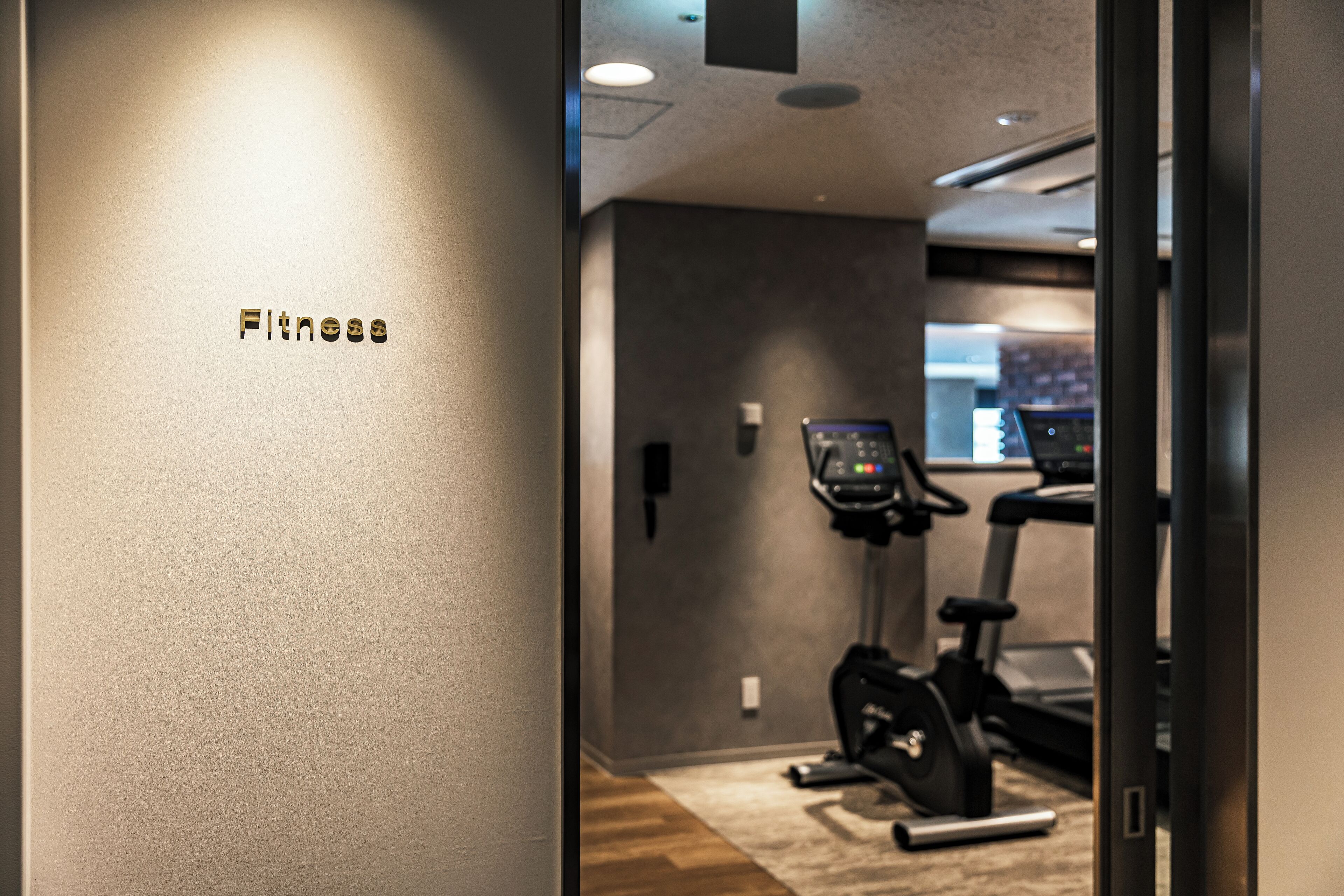 Une salle de remise en forme équipée de matériel d’exercice et dotée d’un panneau de commande fixé au mur.