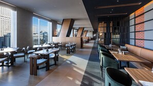 A modern restaurant with high ceilings, large windows, and a mix of wooden and upholstered seating. - THE GATE HOTEL SAPPORO by HULIC (Sapporo)