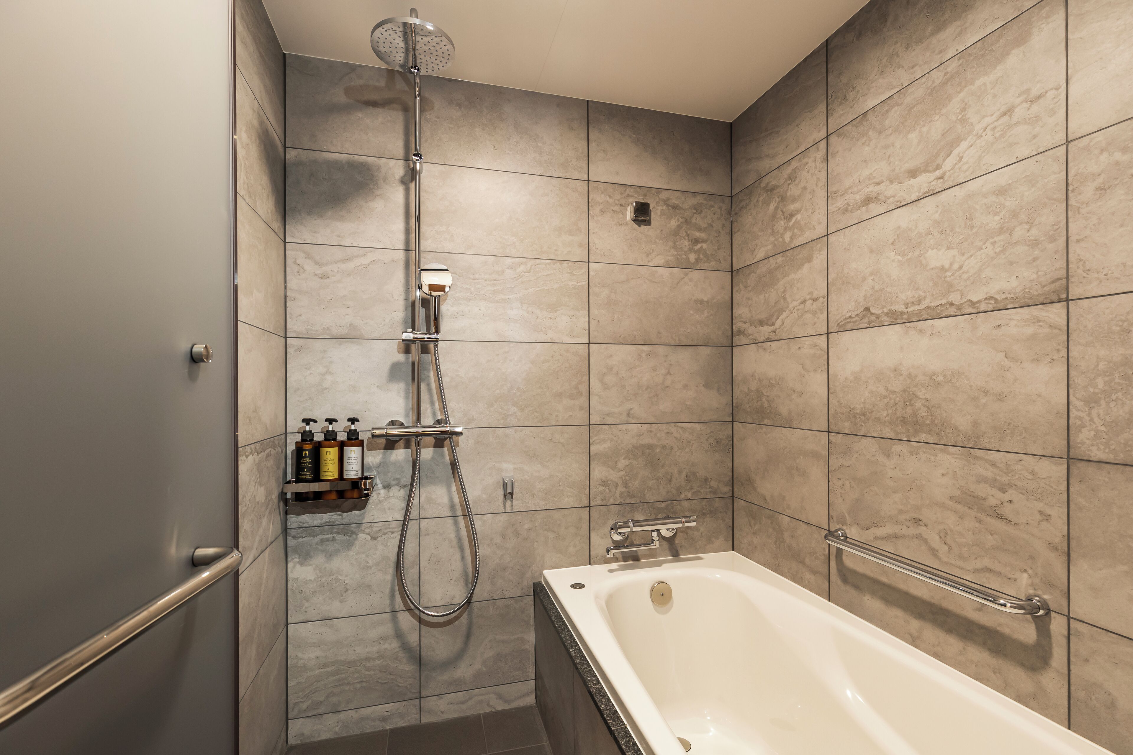 Une salle de bain équipée d’une baignoire, d’une douche et d’une étagère où sont rangés les articles de toilette.