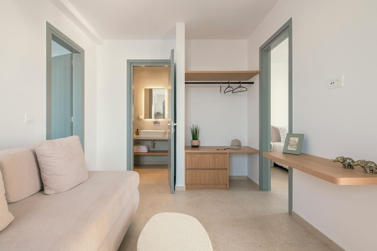 Un dormitorio moderno con cama, escritorio y baño visible a través de una puerta abierta.