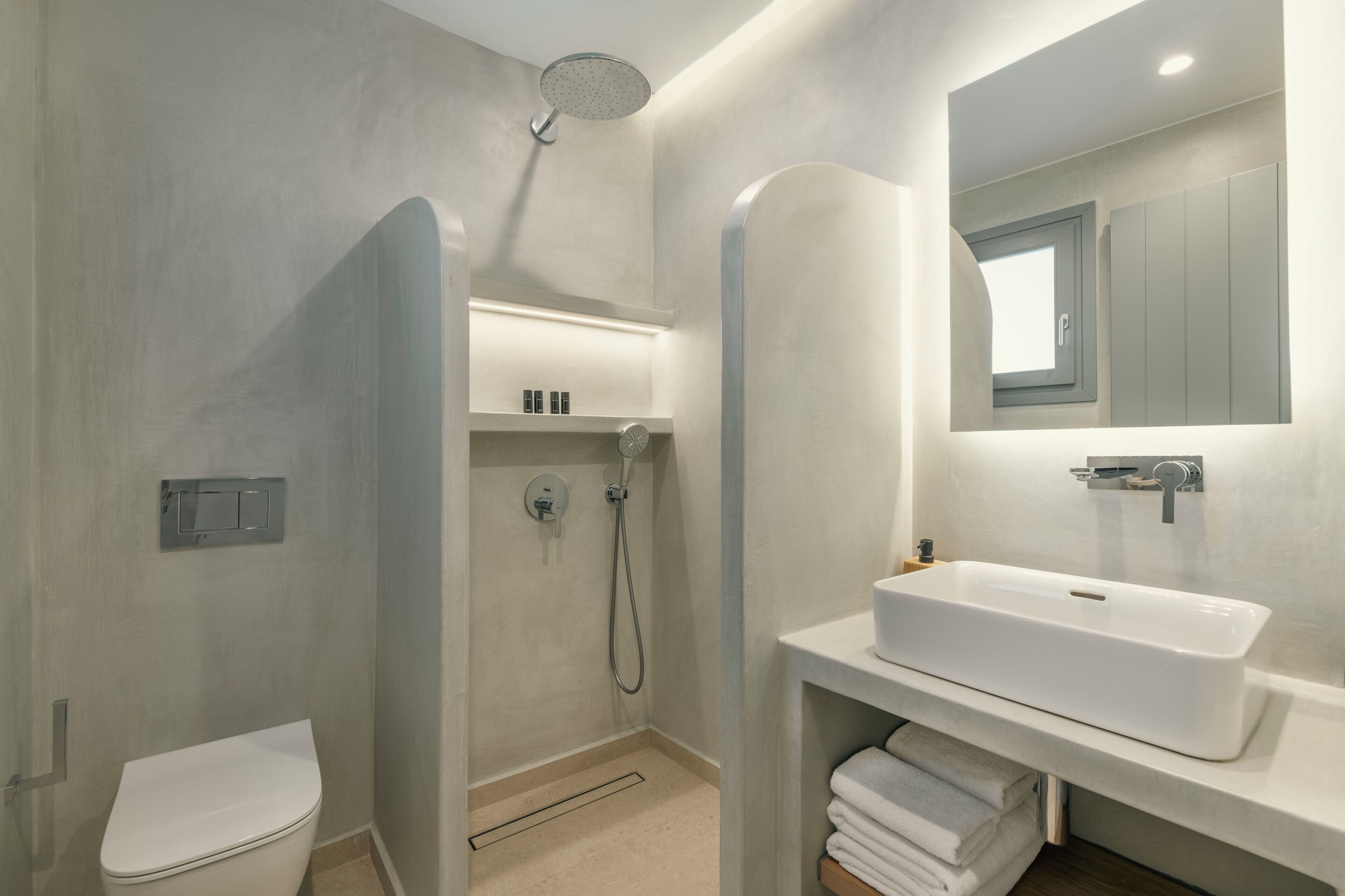 A modern bathroom with a toilet, shower, and sink.
