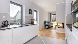A modern kitchen with white cabinets, a black kettle, and a built-in oven. - Cozy vacation home Elisa, house with fireplace, sauna, terrace, garden (Dranske-Lancken)