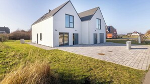 A modern two-story house with a paved driveway and a well-maintained lawn. - Cozy vacation home Elisa, house with fireplace, sauna, terrace, garden (Dranske-Lancken)